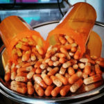 Adderall pills displayed spilling out of a pills cup on a metallic surface